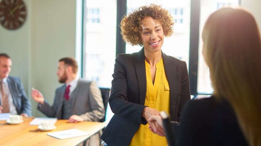 a member of an interview panel greets the next candidate for the job.