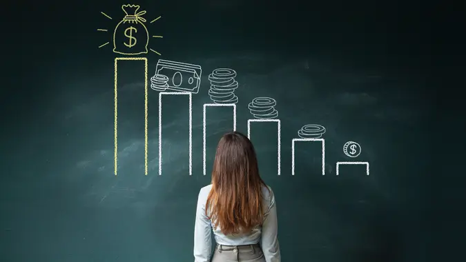 Business woman standing in front of a blackboard with a financial chart.