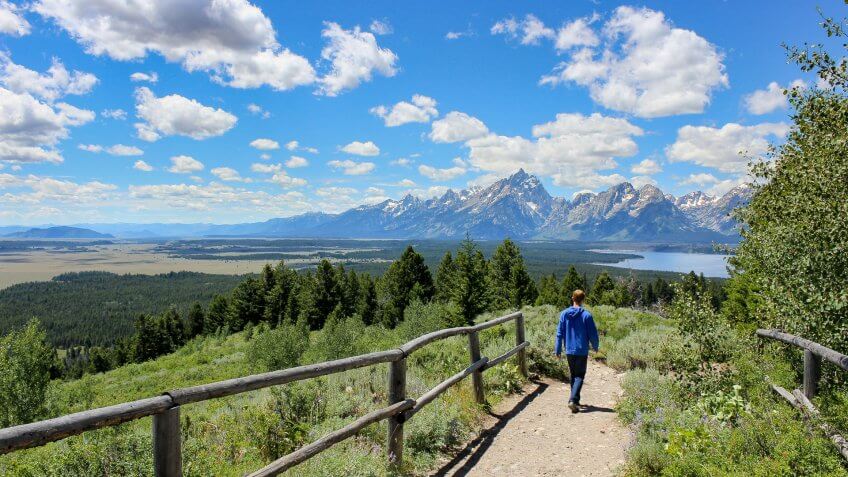 Teenage boy hiking with Jackson lake and mount Teton view in summer.