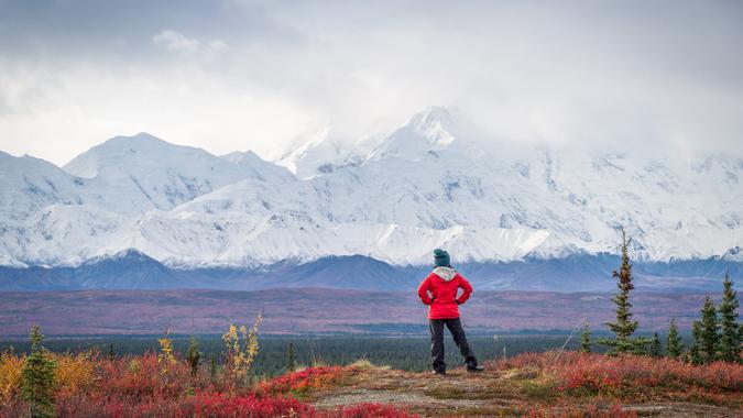 Hiker at mountain top with direct view of the Denali Mountain.