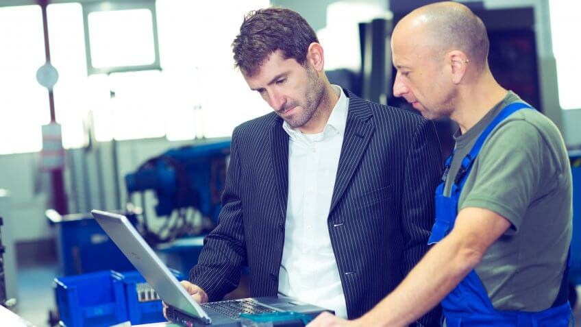 in the factory- boss and worker on work bench.