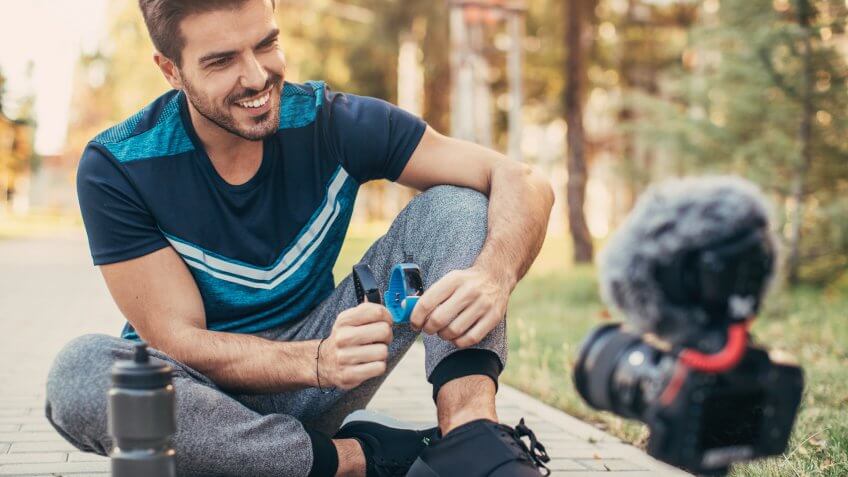 Sportsman reviewing two smart watches for a vlog outside.