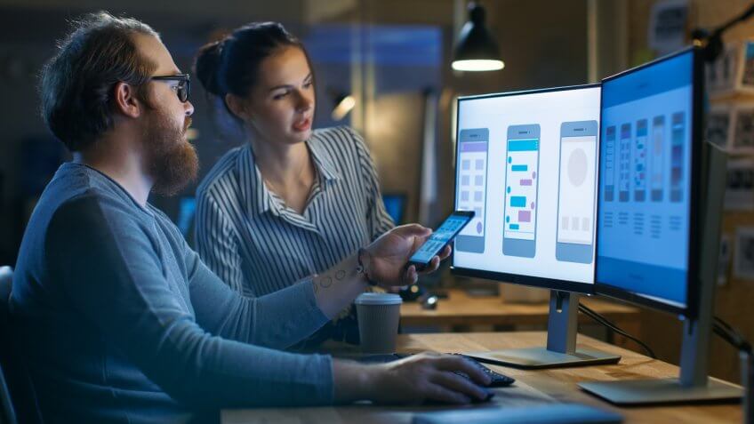 Male and Female Mobile Application Designers Test and Discuss New App Features.