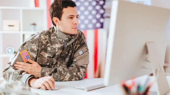 Young soldier man using a computer into his office.