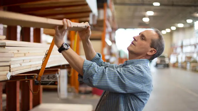 Adult male customer in hardware store choosing lumber for his home improvement project.