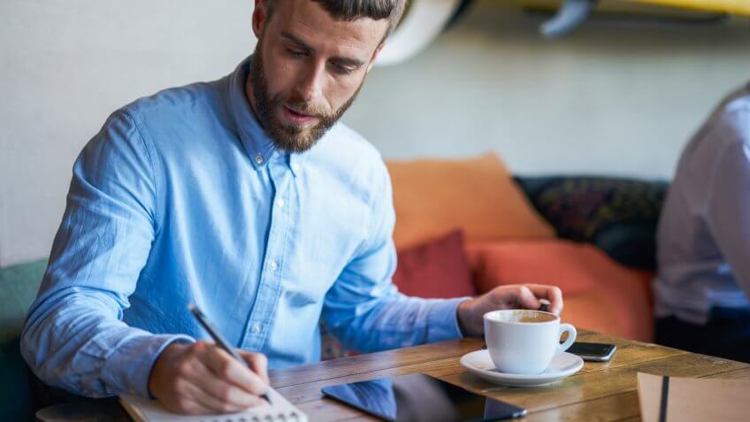 Man writing in notebook at cafe