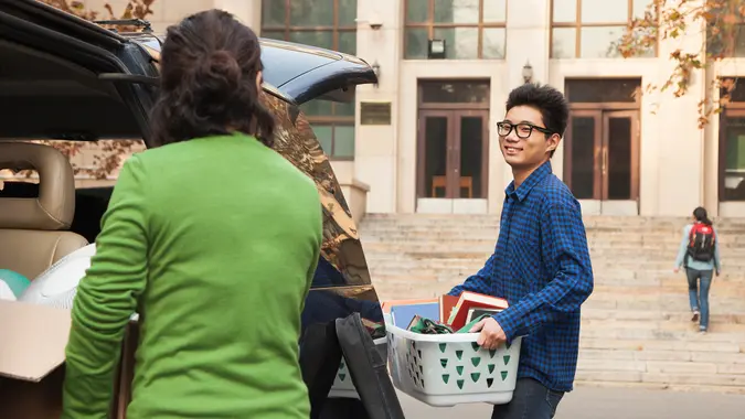 Young man moving into dormitory on college campus.