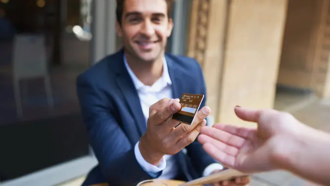 Young businessman paying for his coffee with a credit card at the cafe.