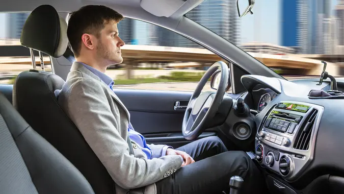 Side View Of A Young Man Sitting Inside Autonomous Car.