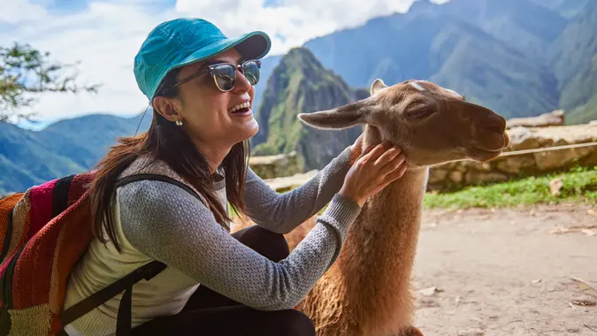 Smiling tourist woman with lama in Machu Picchu hiking travel.