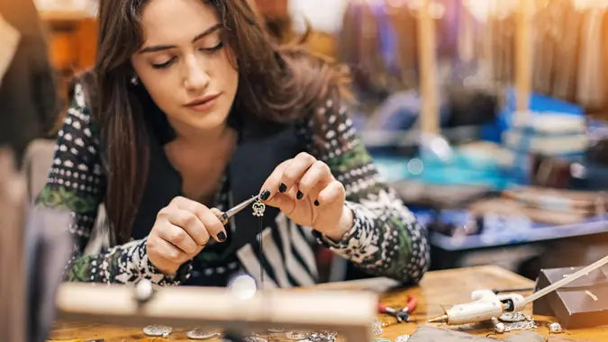 Young woman creating handmade jewelry in her studio.