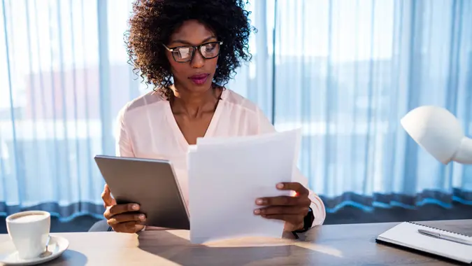 Businesswoman holding a tablet and reading a document in office.