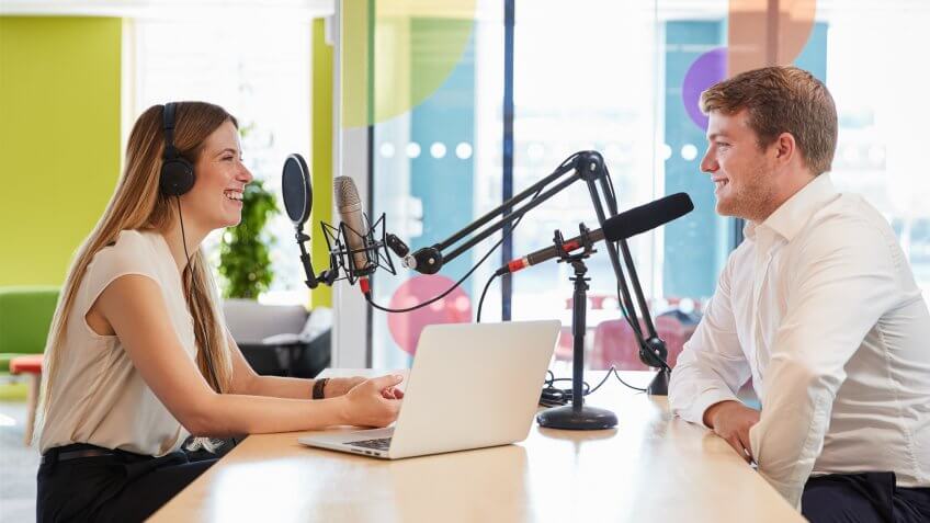 Young woman interviewing a guest in a studio for a podcast.