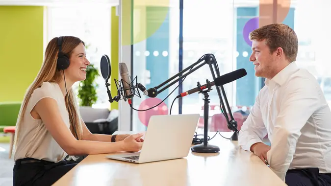 Young woman interviewing a guest in a studio for a podcast.