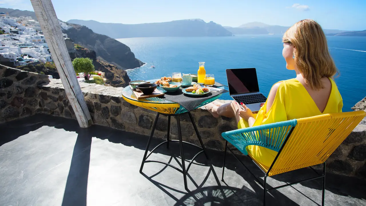 Woman working with laptop while on vacation in Mediterranean.