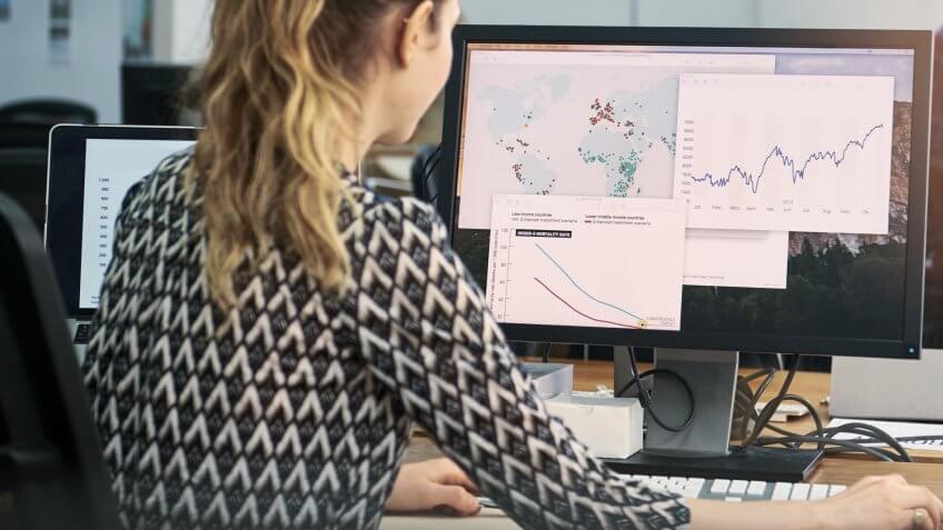 Shot of a young woman using a computer at her desk in a modern office.