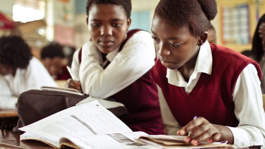 South African girls (from the Xhosa tribe) working together on their studies at an old worn desk in a class room in the Transkei region of rural South Africa.