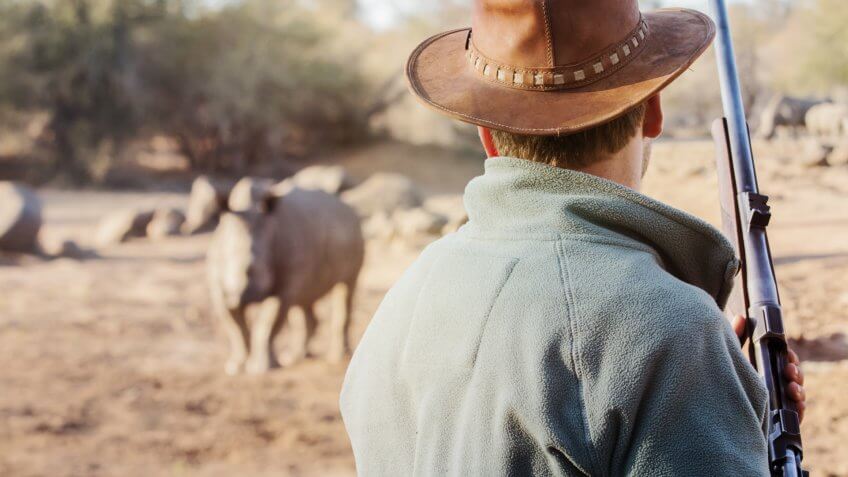 ranger with firearm and rhino in distance