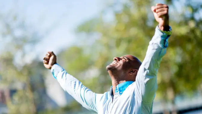 Happy business man with arms up celebrating a promotion.