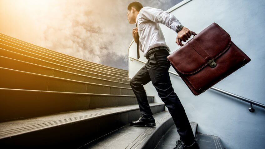 Businessman leap up the stairs to the light.