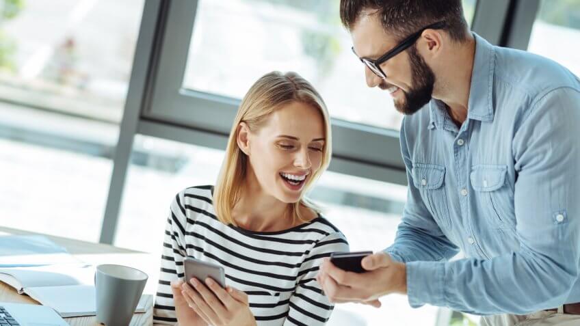 Cheerful colleagues laughing while watching funny videos.
