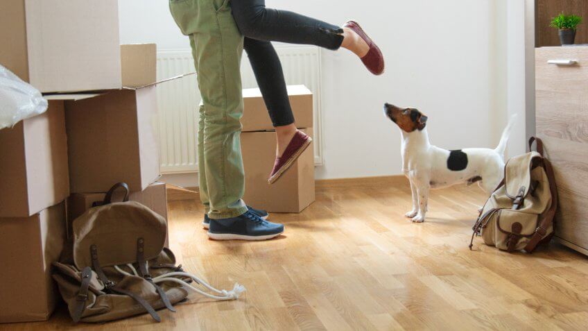 Happy man lifting woman in new house.