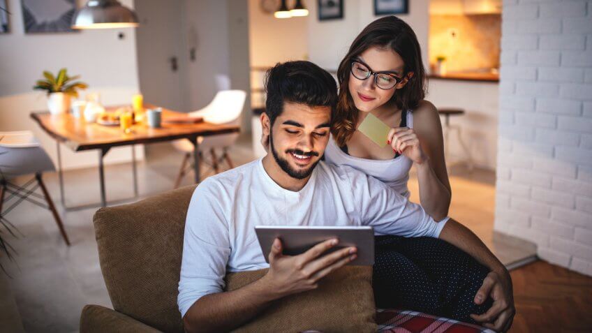 Photo of a young couple shopping online over digital tablet.