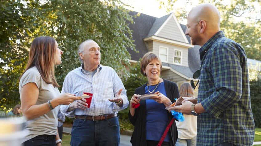 Middle aged and senior neighbours talking at a block party.