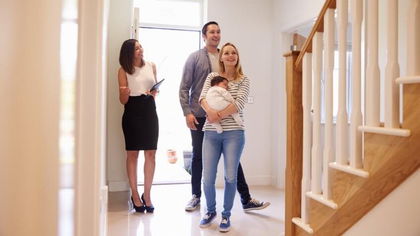 Realtor Showing Young Family Around Property For Sale.