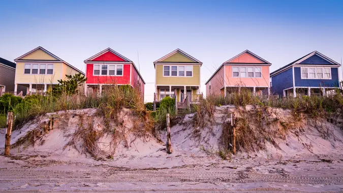 A summer scene on the beach with cottages in a line.