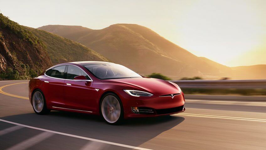 Tesla Model S Red driving at sunset