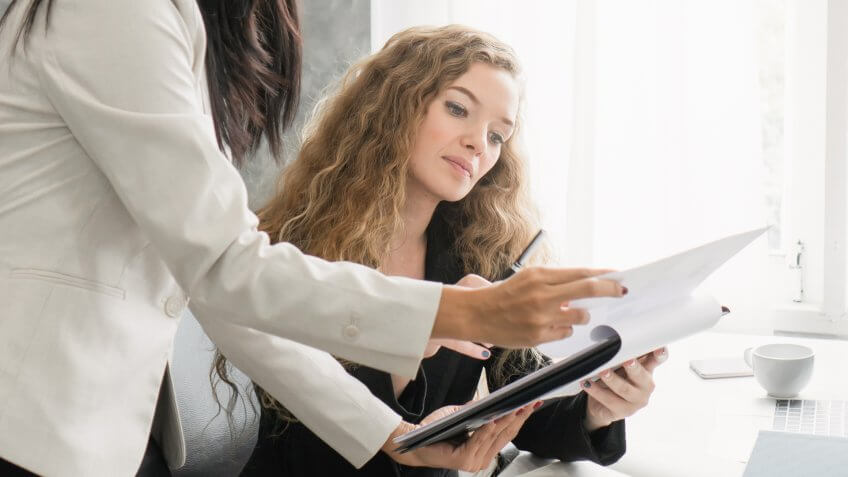 Two business colleagues discussing document in office.