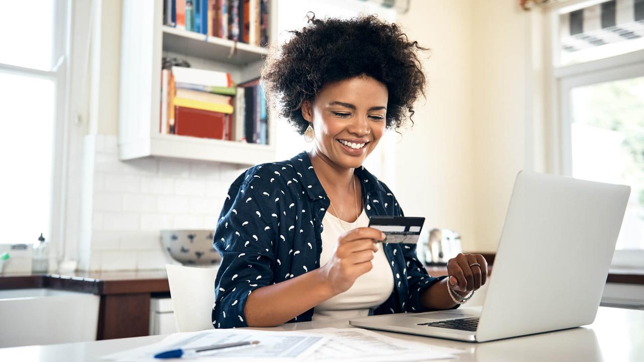 woman smiling at credit card in her home