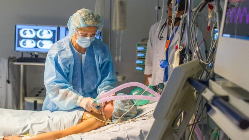 Anesthesiologist using oxygen mask on patient in operating theatre.