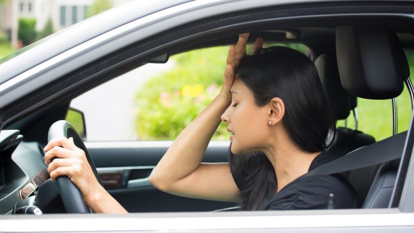 Closeup portrait, angry young sitting woman pissed off by drivers in front of her, hand on head, isolated city street background.