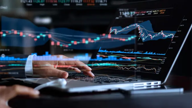 Businessman with statistic graph of stock market financial indices analysis on laptop screen, finance data and technology concept.