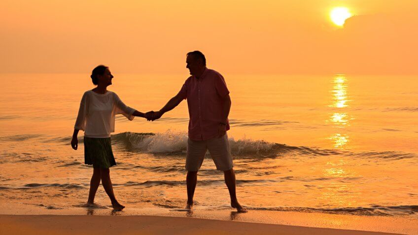 Senior couple walking at beach.