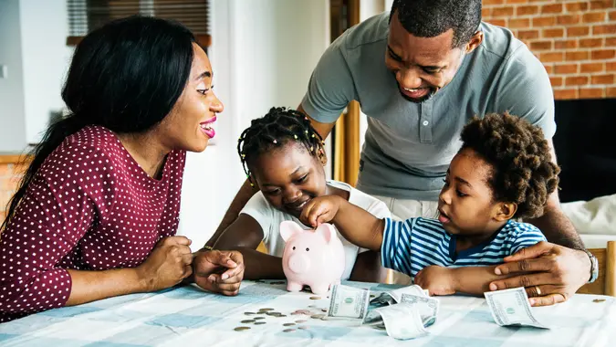 Family saving money to piggy bank.