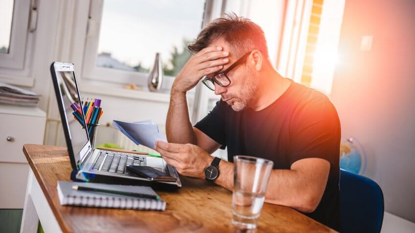 Man sitting in home office, reading letter and felling worried.
