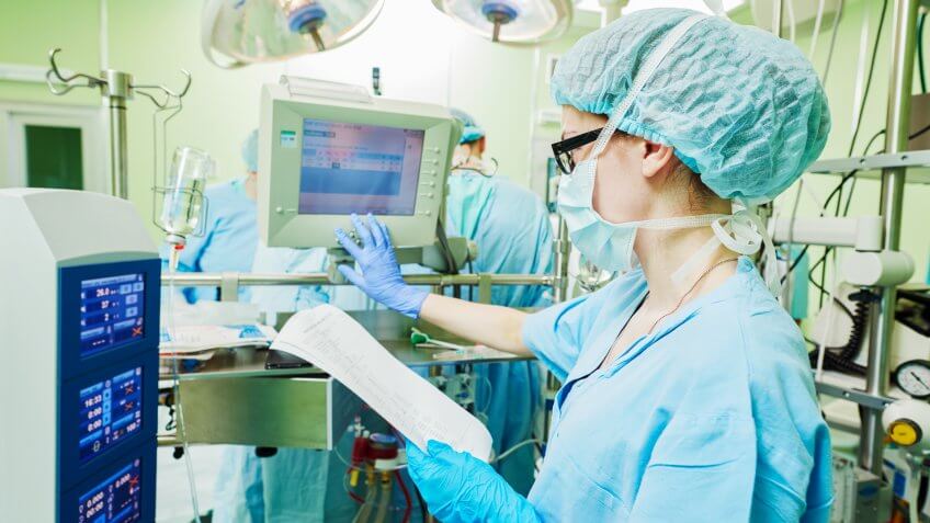 anesthesiologist operating a modern heart lung machine with artificial cardiac valve at operation room in cardiology clinic.