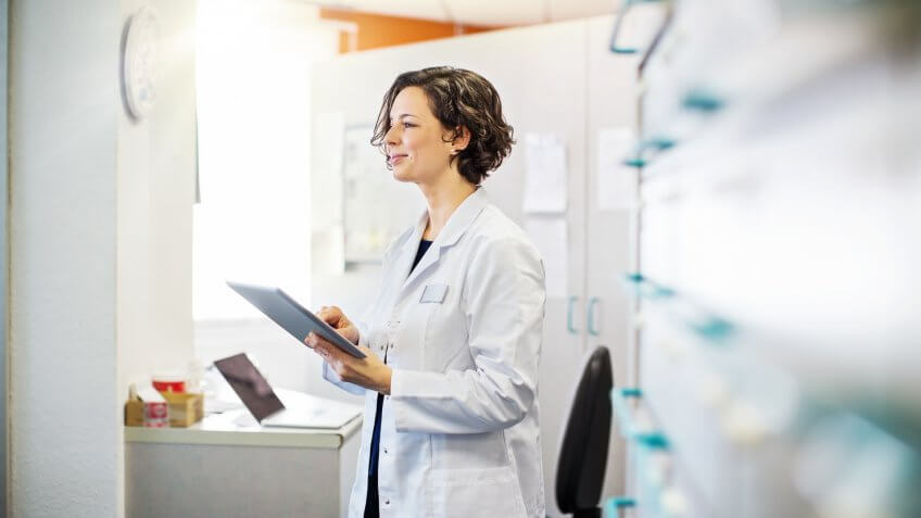 Female pharmacist with a digital tablet standing at chemist store.
