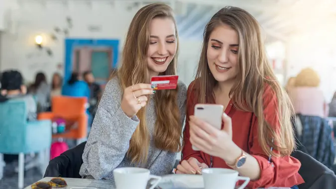 Female friends drinking coffee and shopping online.