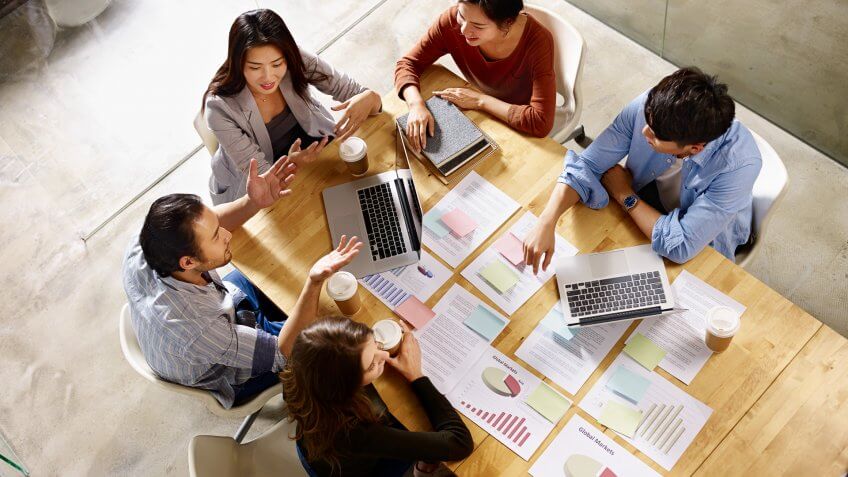 high angle view of a team of asian and caucasian corporate executives discussing business in meeting room.