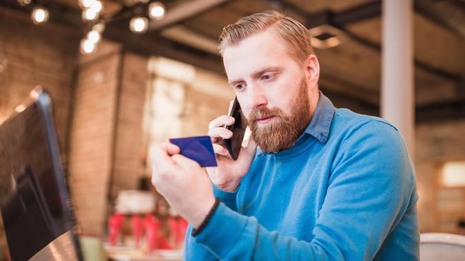 Young, redhead businessman, on coffee break browsing internet, making oline purchase with credit card.