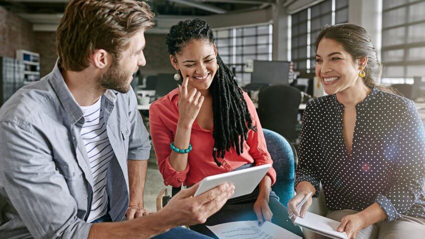 Shot of a group of colleagues using a digital tablet during a brainstorming session in a modern office.