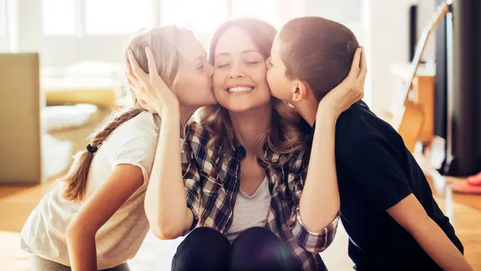 Close up photo of son and daughter kissing their mom.