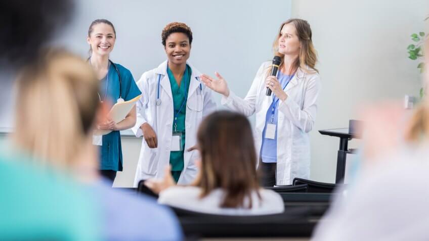 Confident diverse female healthcare professionals speak at a healthcare conference.