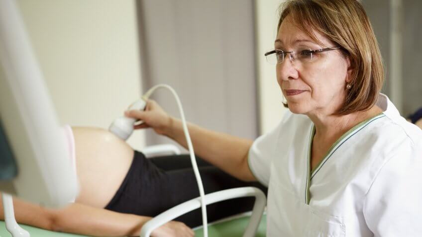 Doctor performing ultrasound on a pregnant woman.