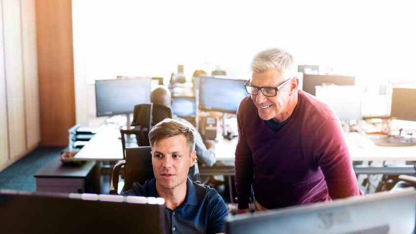 Businessman discussing with coworker at desk.