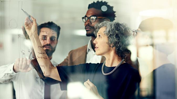 Cropped shot of a group of businesspeople brainstorming with notes on a glass wall in an office.